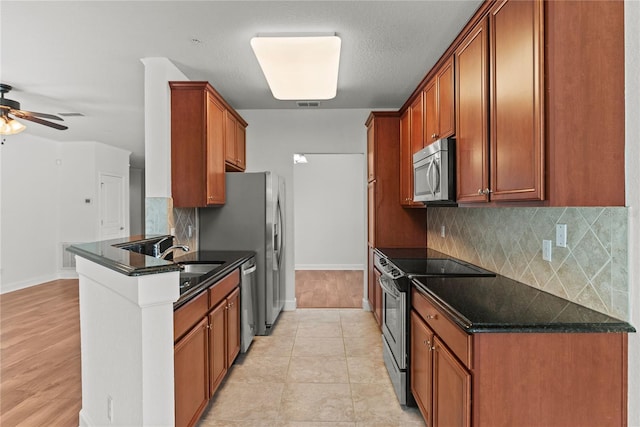 8362 Bella Tierra Ct Unit 10146, Davenport, FL 33896 - kitchen with stainless steel appliances, a peninsula, ceiling fan, backsplash, and brown cabinetry
