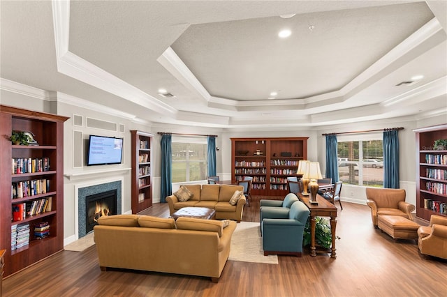 8362 Bella Tierra Ct Unit 10146, Davenport, FL 33896 - living room featuring a raised ceiling, wood finished floors, a fireplace with flush hearth, crown molding, and built in shelves