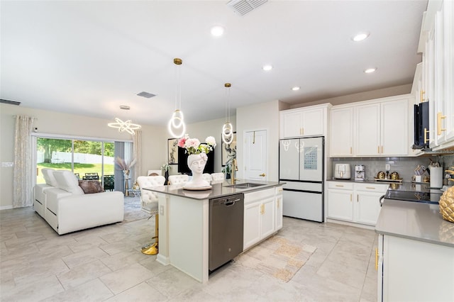4828 Magnetite Loop, Mount Dora, FL 32757 - kitchen featuring dishwashing machine, freestanding refrigerator, stainless steel microwave, decorative backsplash, and white cabinets