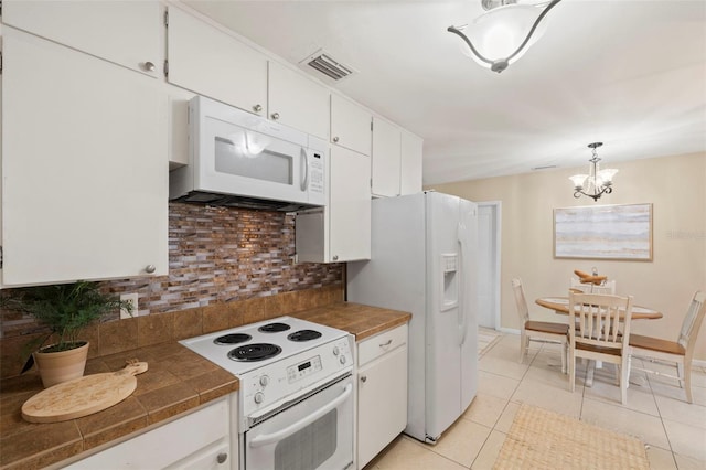 575 Ave M SE, Winter Haven, FL 33880 - kitchen with white appliances, decorative backsplash, white cabinetry, light tile patterned flooring, and tile counters