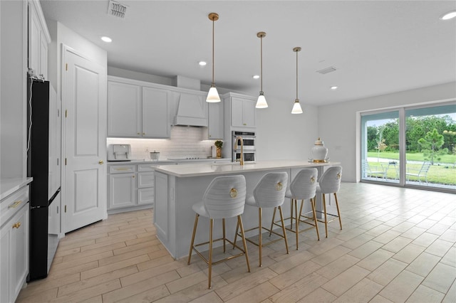 17571 Saw Palmeto Ave, Clermont, FL 34714 - kitchen featuring freestanding refrigerator, double oven, custom exhaust hood, decorative backsplash, and light countertops