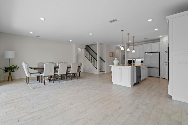 17571 Saw Palmeto Ave, Clermont, FL 34714 - kitchen featuring appliances with stainless steel finishes, a kitchen island with sink, light wood-style floors, recessed lighting, and decorative light fixtures