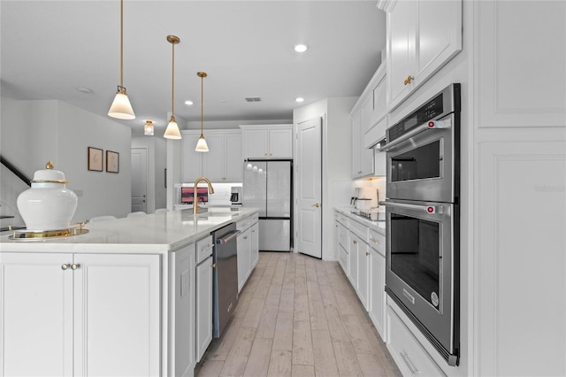 17571 Saw Palmeto Ave, Clermont, FL 34714 - kitchen with stainless steel appliances, white cabinets, an island with sink, pendant lighting, and recessed lighting