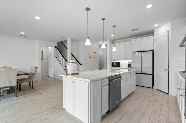 17571 Saw Palmeto Ave, Clermont, FL 34714 - kitchen with appliances with stainless steel finishes, light wood-type flooring, light countertops, recessed lighting, and a kitchen island with sink