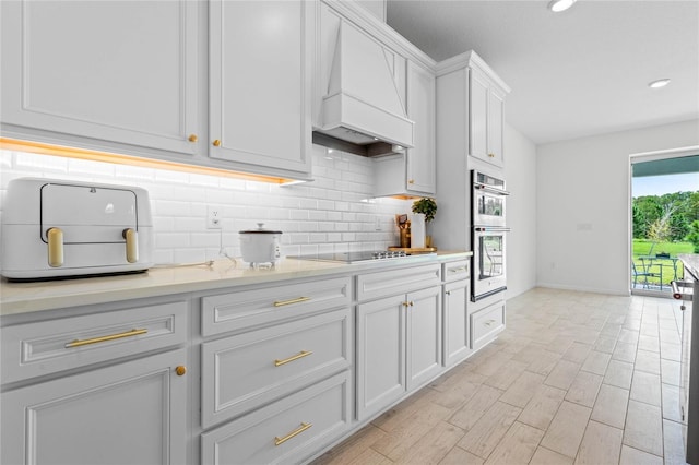 17571 Saw Palmeto Ave, Clermont, FL 34714 - kitchen featuring custom range hood, double oven, black electric stovetop, tasteful backsplash, and light countertops