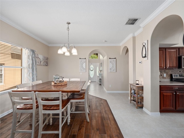 2454 Black Lake Blvd, Winter Garden, FL 34787 - dining area featuring arched walkways, ornamental molding, a chandelier, and light tile patterned floors
