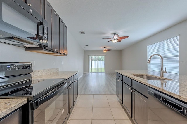 12104 Fawn Brindle St, Riverview, FL 33578 - kitchen with black appliances, a ceiling fan, light stone countertops, and light tile patterned floors