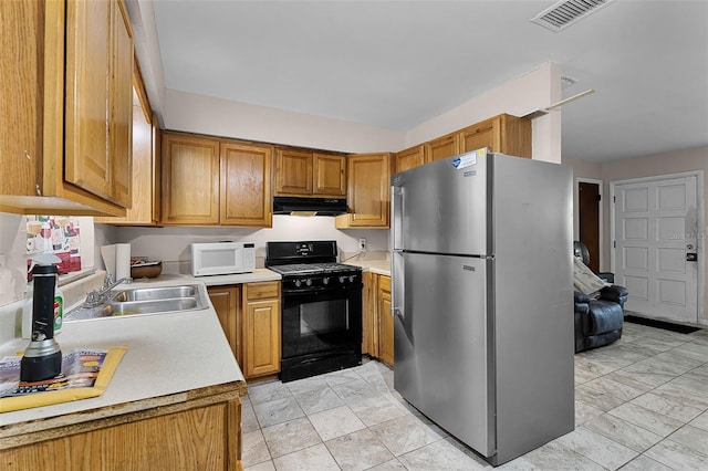 770 W Webster Ave, Winter Park, FL 32789 - kitchen with freestanding refrigerator, black gas range oven, under cabinet range hood, white microwave, and light countertops