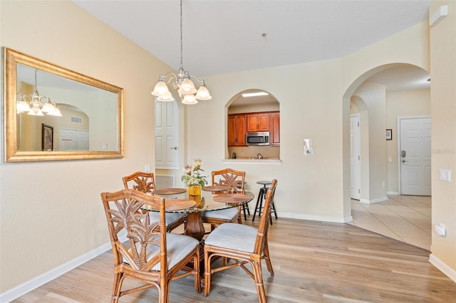 4024 Breakview Dr Unit 402, Orlando, FL 32819 - dining space featuring light wood-type flooring, a chandelier, and arched walkways