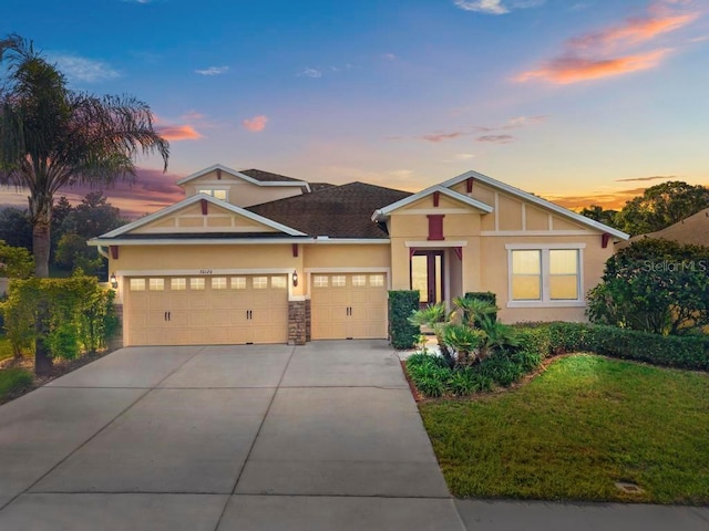 30120 Hackney Loop, Mount Dora, FL 32757 - view of front of home featuring an attached garage, stucco siding, driveway, stone siding, and a yard