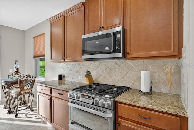 30120 Hackney Loop, Mount Dora, FL 32757 - kitchen featuring appliances with stainless steel finishes, light stone countertops, decorative backsplash, and brown cabinets