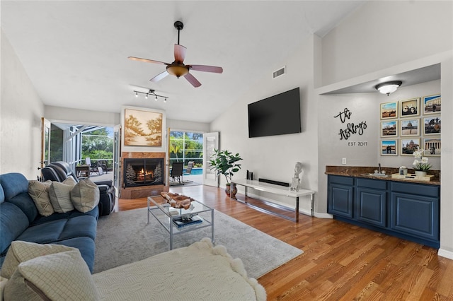 5949 Broken Bow Ln, Port Orange, FL 32127 - living room with bar with sink, light wood-style flooring, ceiling fan, lofted ceiling, and a tiled fireplace