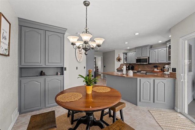 5949 Broken Bow Ln, Port Orange, FL 32127 - kitchen with stainless steel appliances, gray cabinets, a chandelier, light tile patterned flooring, and a peninsula