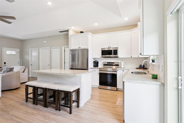 430 Baker Ave, Lake Helen, FL 32744 - kitchen with stainless steel appliances, a kitchen bar, light wood-style floors, white cabinets, and recessed lighting