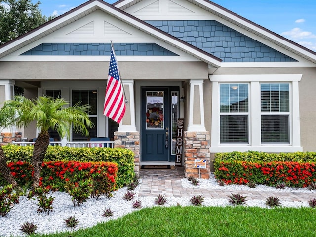 14903 Ellingsworth Ln, Winter Garden, FL 34787 - view of exterior entry featuring stucco siding, covered porch, and stone siding