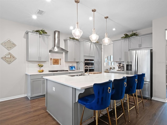 14903 Ellingsworth Ln, Winter Garden, FL 34787 - kitchen featuring wall chimney range hood, appliances with stainless steel finishes, dark wood-style flooring, a kitchen breakfast bar, and recessed lighting