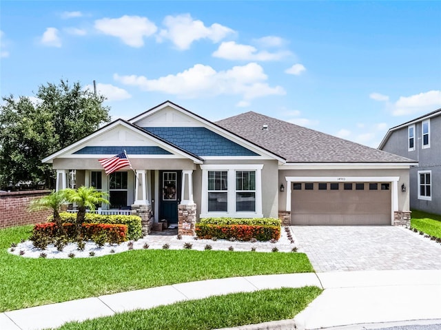 14903 Ellingsworth Ln, Winter Garden, FL 34787 - craftsman-style house featuring covered porch, stone siding, a garage, a front yard, and decorative driveway