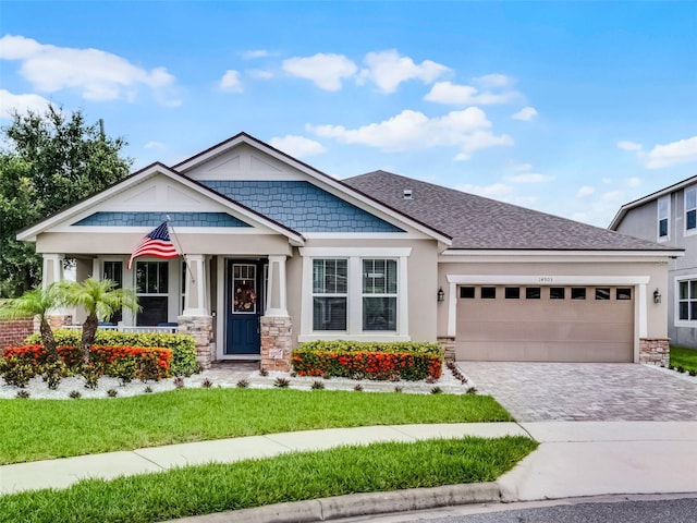 14903 Ellingsworth Ln, Winter Garden, FL 34787 - craftsman-style house featuring an attached garage, decorative driveway, stone siding, and a front yard