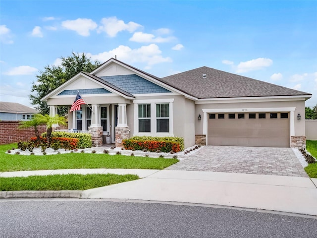 14903 Ellingsworth Ln, Winter Garden, FL 34787 - craftsman inspired home with stone siding, stucco siding, decorative driveway, covered porch, and an attached garage