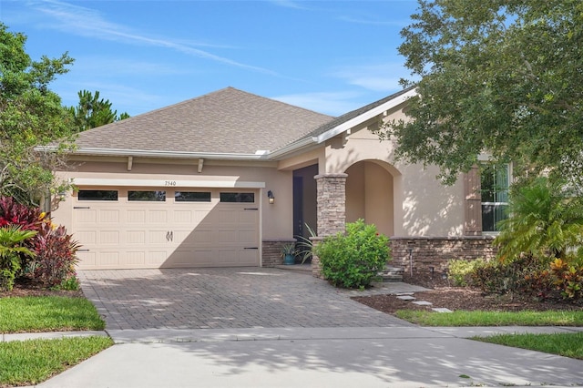7540 Bishop Square Dr, Winter Garden, FL 34787 - view of front of house featuring stucco siding, decorative driveway, an attached garage, stone siding, and a shingled roof