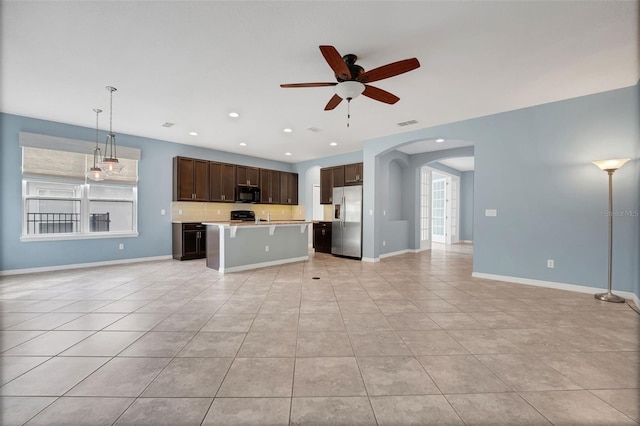 7540 Bishop Square Dr, Winter Garden, FL 34787 - kitchen with stainless steel fridge, black microwave, open floor plan, arched walkways, and a ceiling fan