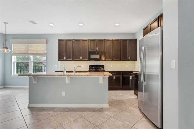 7540 Bishop Square Dr, Winter Garden, FL 34787 - kitchen with freestanding refrigerator, black microwave, dark brown cabinetry, tasteful backsplash, and a breakfast bar area