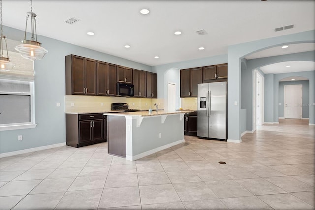 7540 Bishop Square Dr, Winter Garden, FL 34787 - kitchen featuring stainless steel refrigerator with ice dispenser, black microwave, stove, a kitchen breakfast bar, and light tile patterned floors