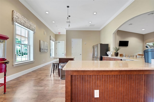 7540 Bishop Square Dr, Winter Garden, FL 34787 - kitchen with freestanding refrigerator, light wood-type flooring, ornamental molding, arched walkways, and a peninsula
