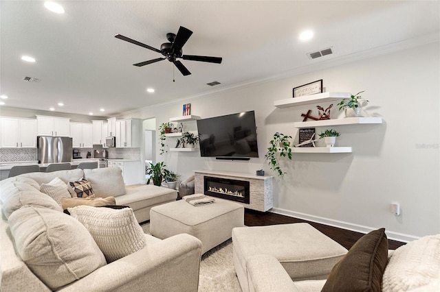 1406 Deuce Cir, Champions Gate, FL 33896 - living room featuring ornamental molding, dark wood-type flooring, a ceiling fan, recessed lighting, and a glass covered fireplace