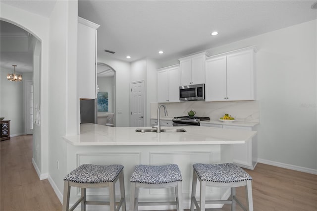11222 Rapallo Ln, Windermere, FL 34786 - kitchen featuring appliances with stainless steel finishes, arched walkways, light wood finished floors, a breakfast bar area, and light countertops
