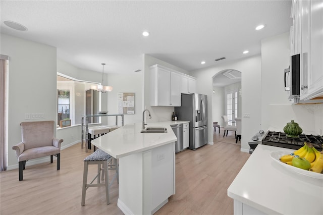11222 Rapallo Ln, Windermere, FL 34786 - kitchen featuring stainless steel appliances, white cabinetry, a breakfast bar area, arched walkways, and light countertops