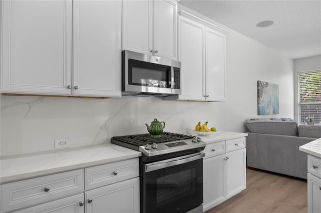 11222 Rapallo Ln, Windermere, FL 34786 - kitchen with appliances with stainless steel finishes, open floor plan, light wood-style flooring, white cabinetry, and light stone countertops
