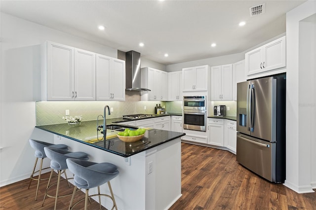 2604 Pinnacle, Clermont, FL 34711 - kitchen with appliances with stainless steel finishes, wall chimney range hood, a peninsula, white cabinetry, and backsplash
