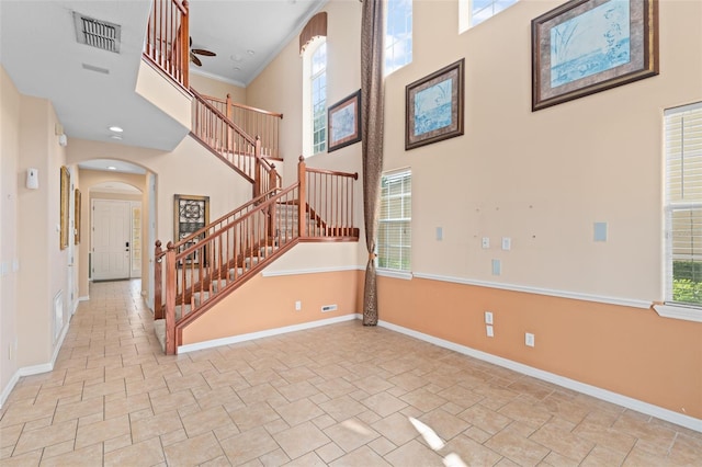 1011 Wood Cv, Kissimmee, FL 34743 - stairs with arched walkways, a towering ceiling, stone finish flooring, healthy amount of natural light, and ornamental molding
