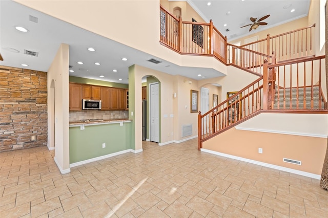 1011 Wood Cv, Kissimmee, FL 34743 - kitchen with stainless steel microwave, a ceiling fan, arched walkways, open floor plan, and tasteful backsplash