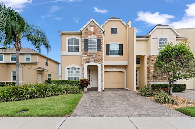 1011 Wood Cv, Kissimmee, FL 34743 - view of front of property with stone siding, stucco siding, decorative driveway, and a front yard