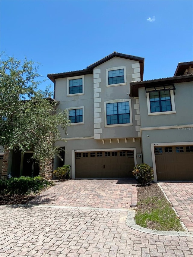 8512 Player Point Dr, Davenport, FL 33896 - view of front facade featuring stucco siding, decorative driveway, and an attached garage