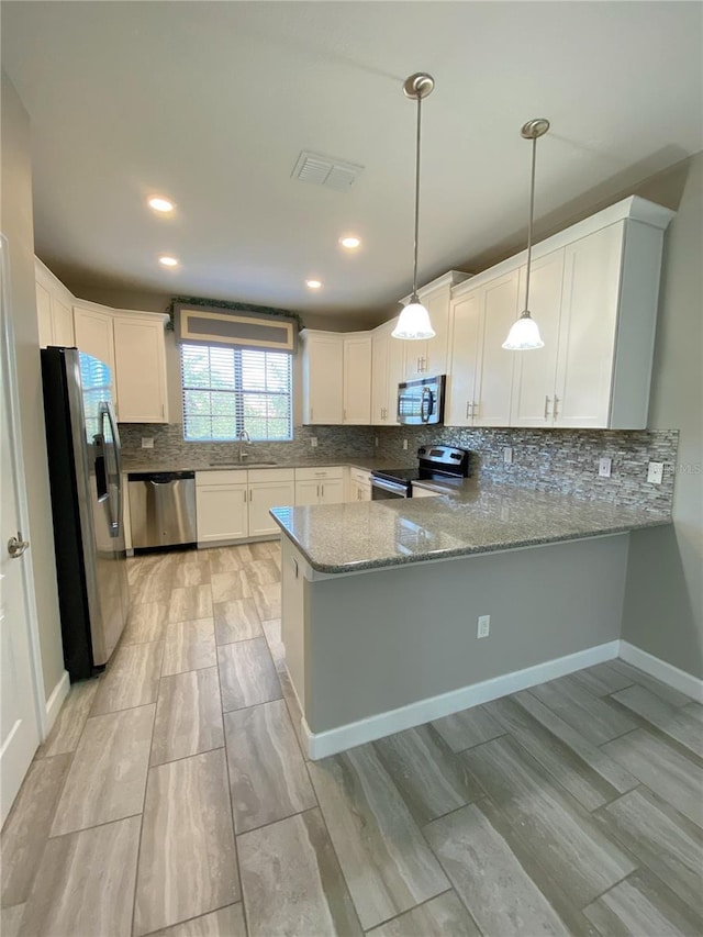 8512 Player Point Dr, Davenport, FL 33896 - kitchen featuring appliances with stainless steel finishes, a peninsula, decorative backsplash, wood tiled floors, and light stone countertops