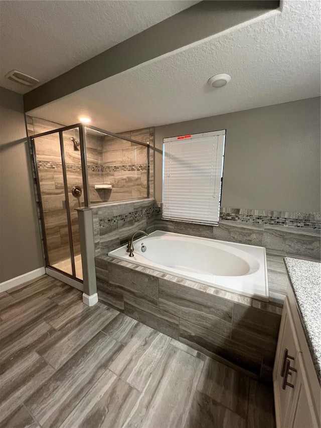 8512 Player Point Dr, Davenport, FL 33896 - full bathroom featuring a garden tub, a shower stall, vanity, wood finished floors, and a textured ceiling