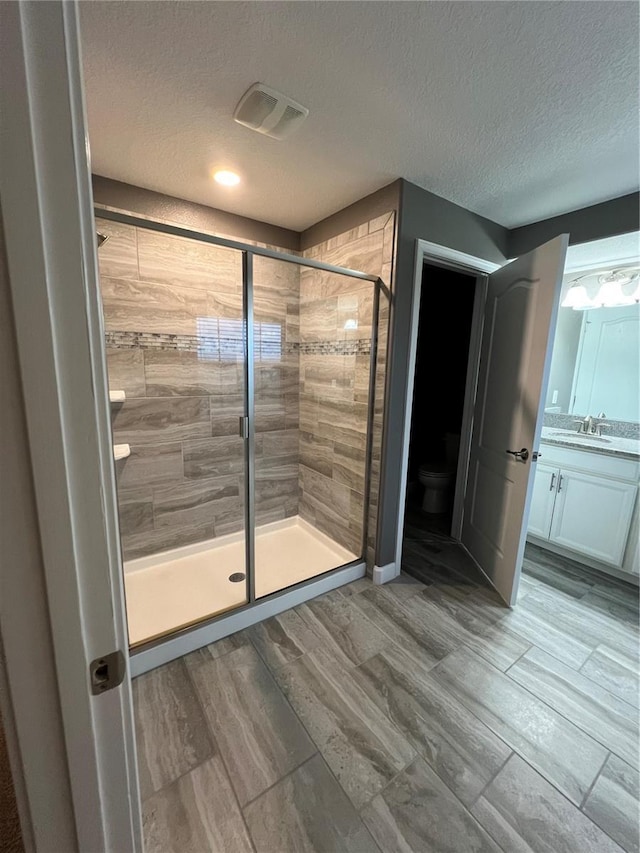 8512 Player Point Dr, Davenport, FL 33896 - bathroom with a shower stall, a textured ceiling, vanity, and wood finished floors