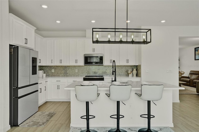2912 Sanctuary Dr, Clermont, FL 34714 - kitchen with high end refrigerator, light countertops, tasteful backsplash, a center island with sink, and recessed lighting