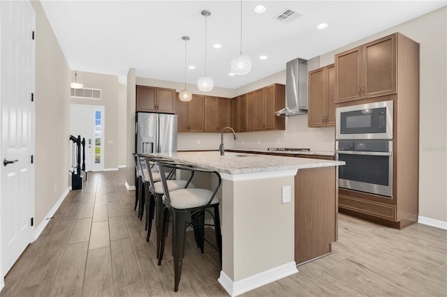 1564 Atlantic Coastline Loop, Oakland, FL 34787 - kitchen featuring stainless steel appliances, wall chimney exhaust hood, light wood-type flooring, a kitchen island with sink, and decorative light fixtures