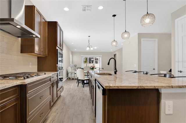 1564 Atlantic Coastline Loop, Oakland, FL 34787 - kitchen featuring wall chimney exhaust hood, appliances with stainless steel finishes, a chandelier, light wood-type flooring, and a large island with sink
