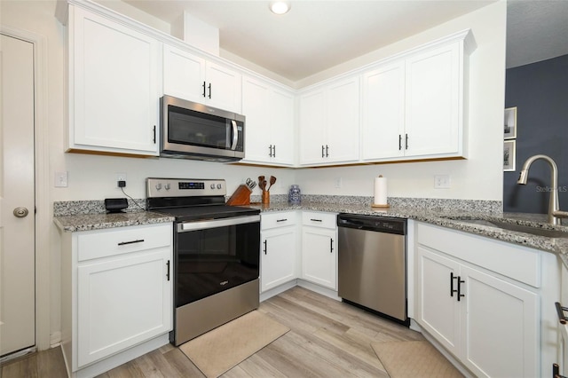 2326 Carrabelle Way, Sanford, FL 32771 - kitchen featuring appliances with stainless steel finishes, light wood-style flooring, white cabinetry, light stone counters, and recessed lighting