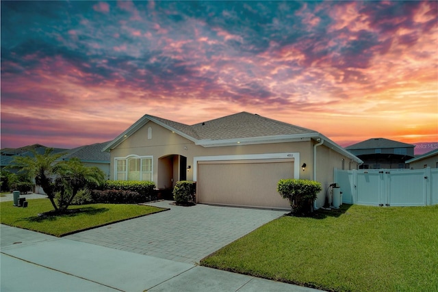 480 Kestrel Dr, Groveland, FL 34736 - ranch-style house with a gate, an attached garage, decorative driveway, stucco siding, and a shingled roof
