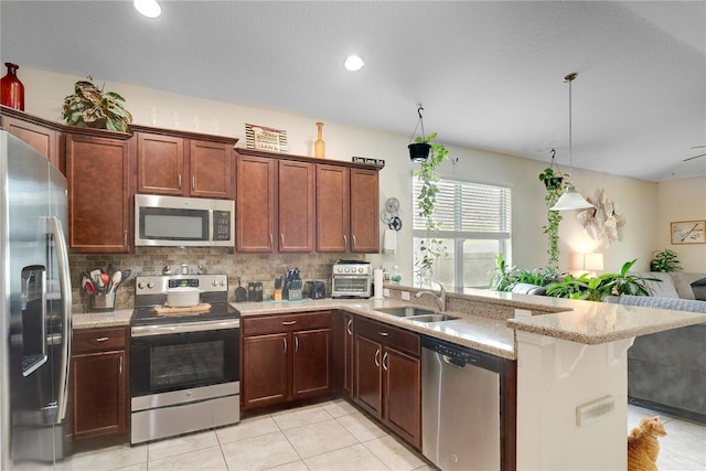 480 Kestrel Dr, Groveland, FL 34736 - kitchen with stainless steel appliances, a peninsula, light stone countertops, light tile patterned floors, and open floor plan