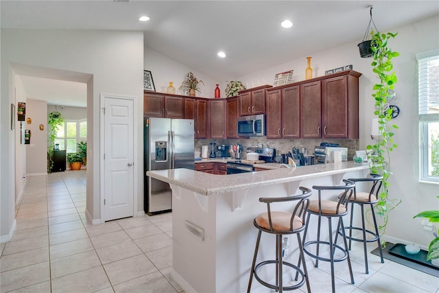 480 Kestrel Dr, Groveland, FL 34736 - kitchen with appliances with stainless steel finishes, a peninsula, backsplash, a kitchen bar, and lofted ceiling