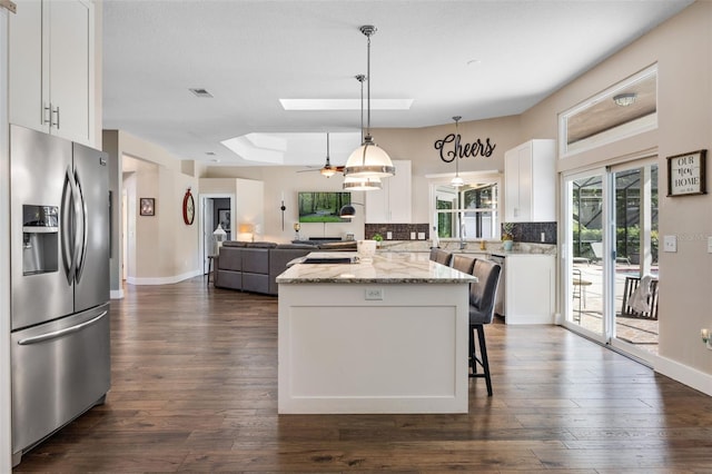 5141 Autumn Ridge Ln, Windermere, FL 34786 - kitchen with stainless steel fridge with ice dispenser, a skylight, a kitchen island, white cabinets, and dark wood-type flooring