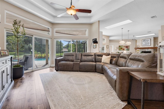 5141 Autumn Ridge Ln, Windermere, FL 34786 - living room with ceiling fan, a skylight, hardwood / wood-style floors, a raised ceiling, and a fireplace