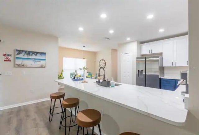365 Aylesbury Ct, Kissimmee, FL 34758 - kitchen with stainless steel fridge with ice dispenser, light countertops, a breakfast bar area, white cabinetry, and a peninsula